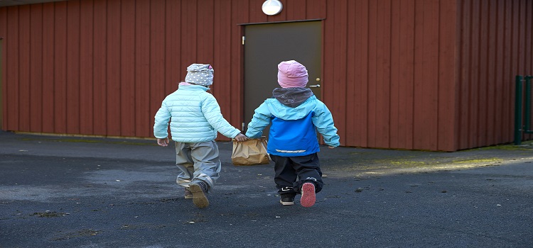 Två barn som bär en matavfallspåse